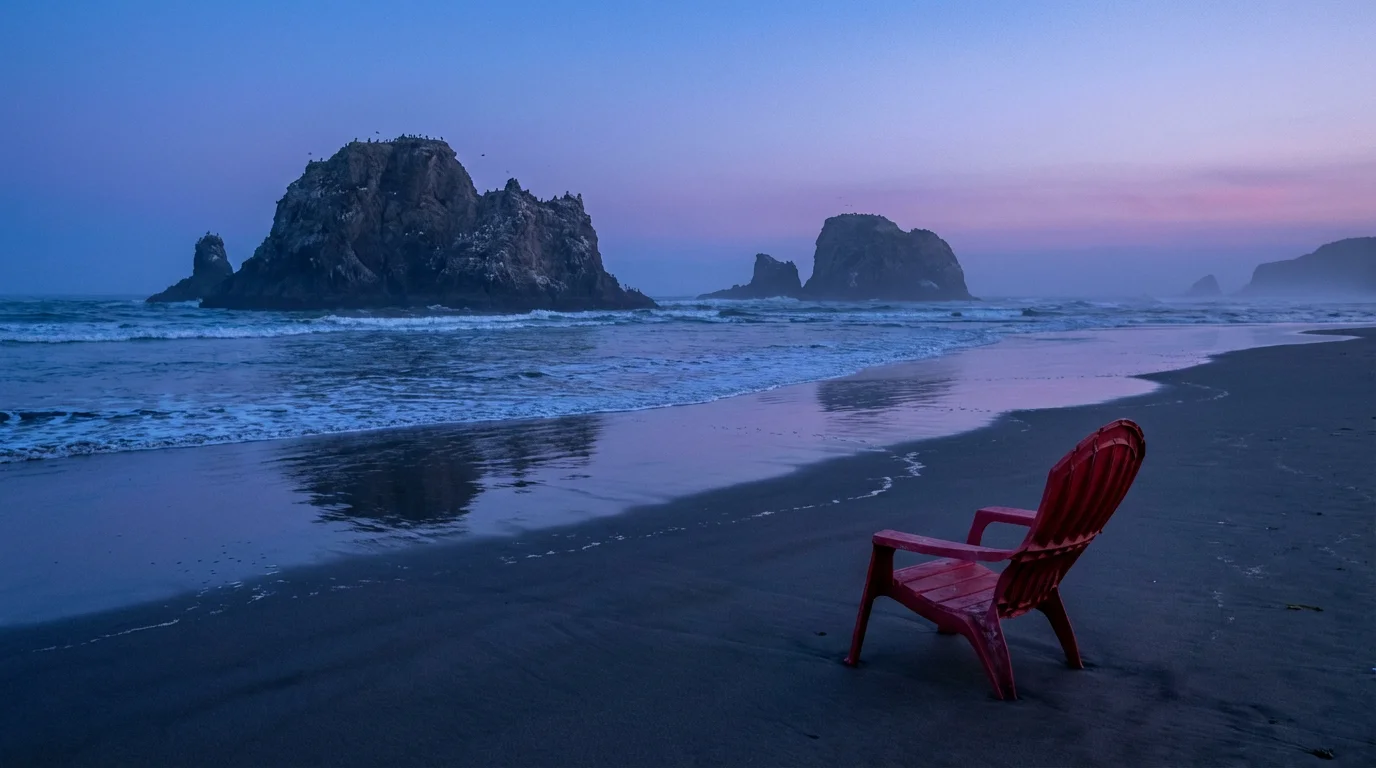 Pristine beach landscape at dusk spoiled by a single red plastic chair in the foreground.