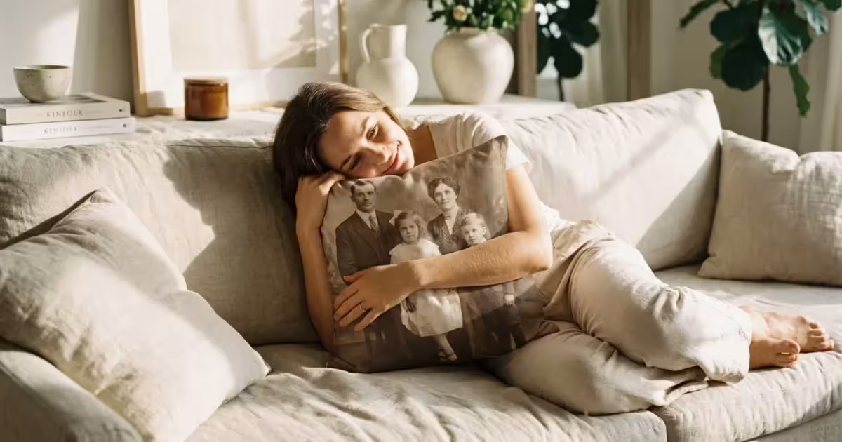 A woman hugging a custom photo pillow in a sunlit living room.