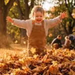 A toddler caught mid-air jumping into autumn leaves during golden hour.